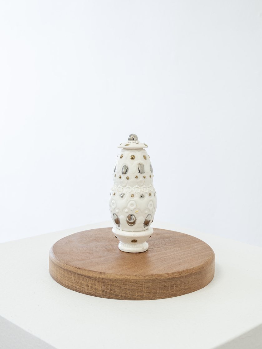small white porcelain perfume bottle on mahogany pedestal vertical