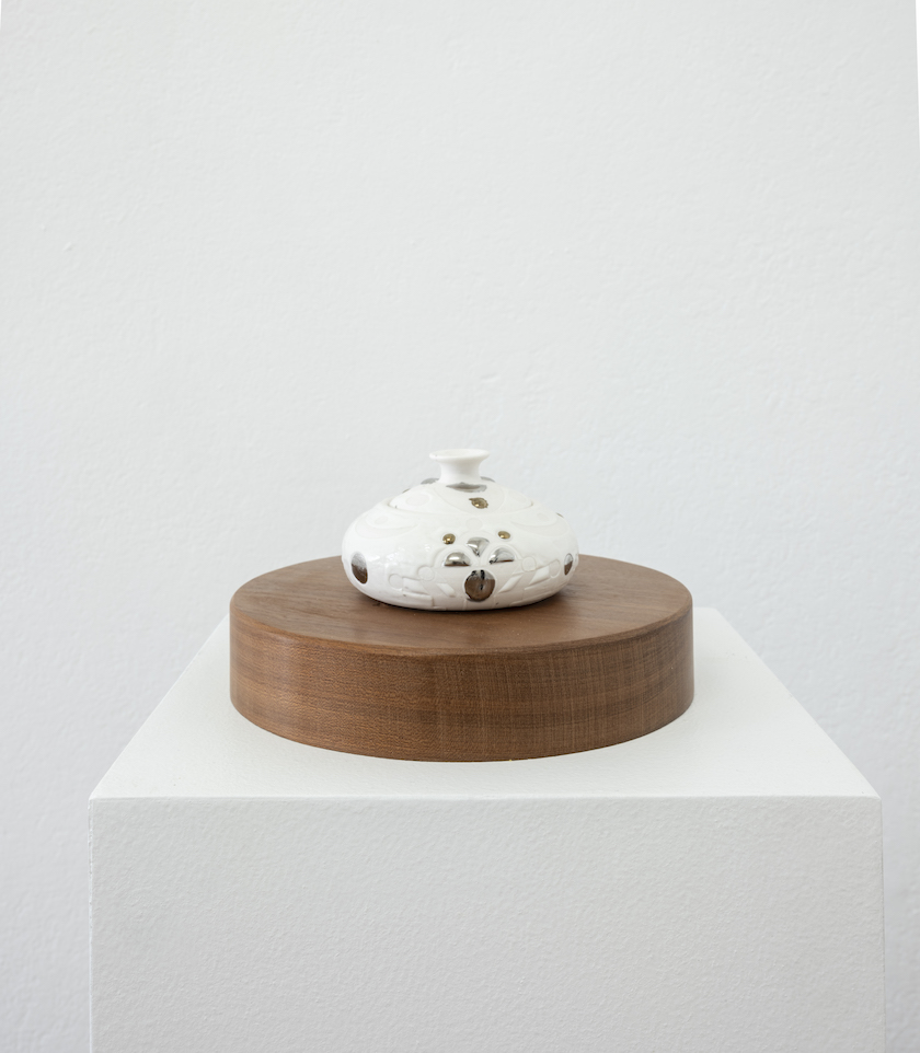 small white porcelain perfume bottle on mahogany pedestal squat
