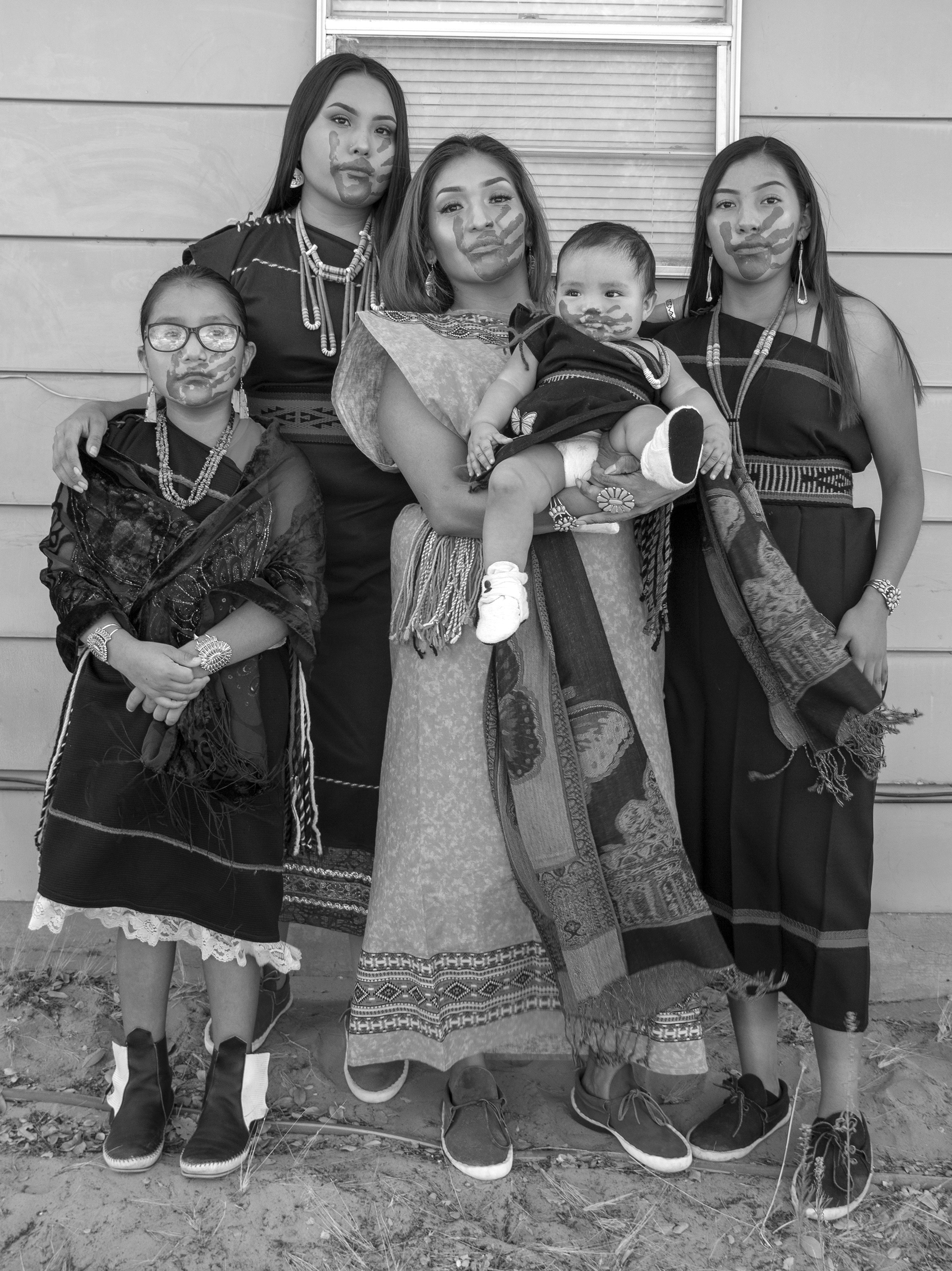 Family of Navajo women with hands over their mouths. Black and white photograph.